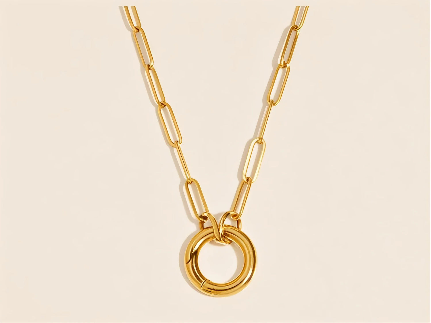 close-up of gold circle pendant and paperclip chain on soft oat beige surface – 14k gold plated stainless steel


